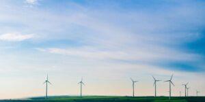 white windmills on green grass field under white clouds and blue sky