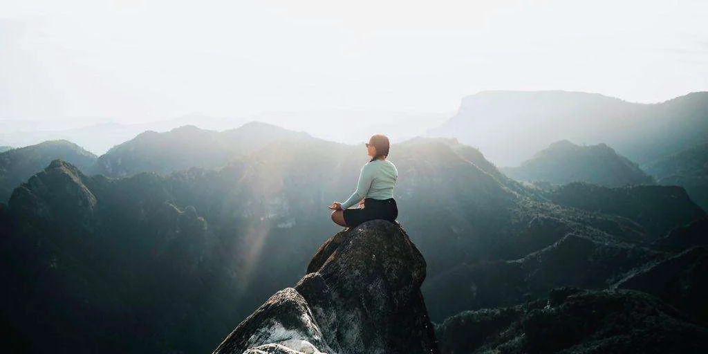 a man sitting on top of a large rock