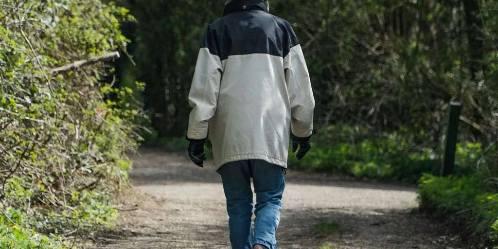 person in white jacket walking on dirt road during daytime